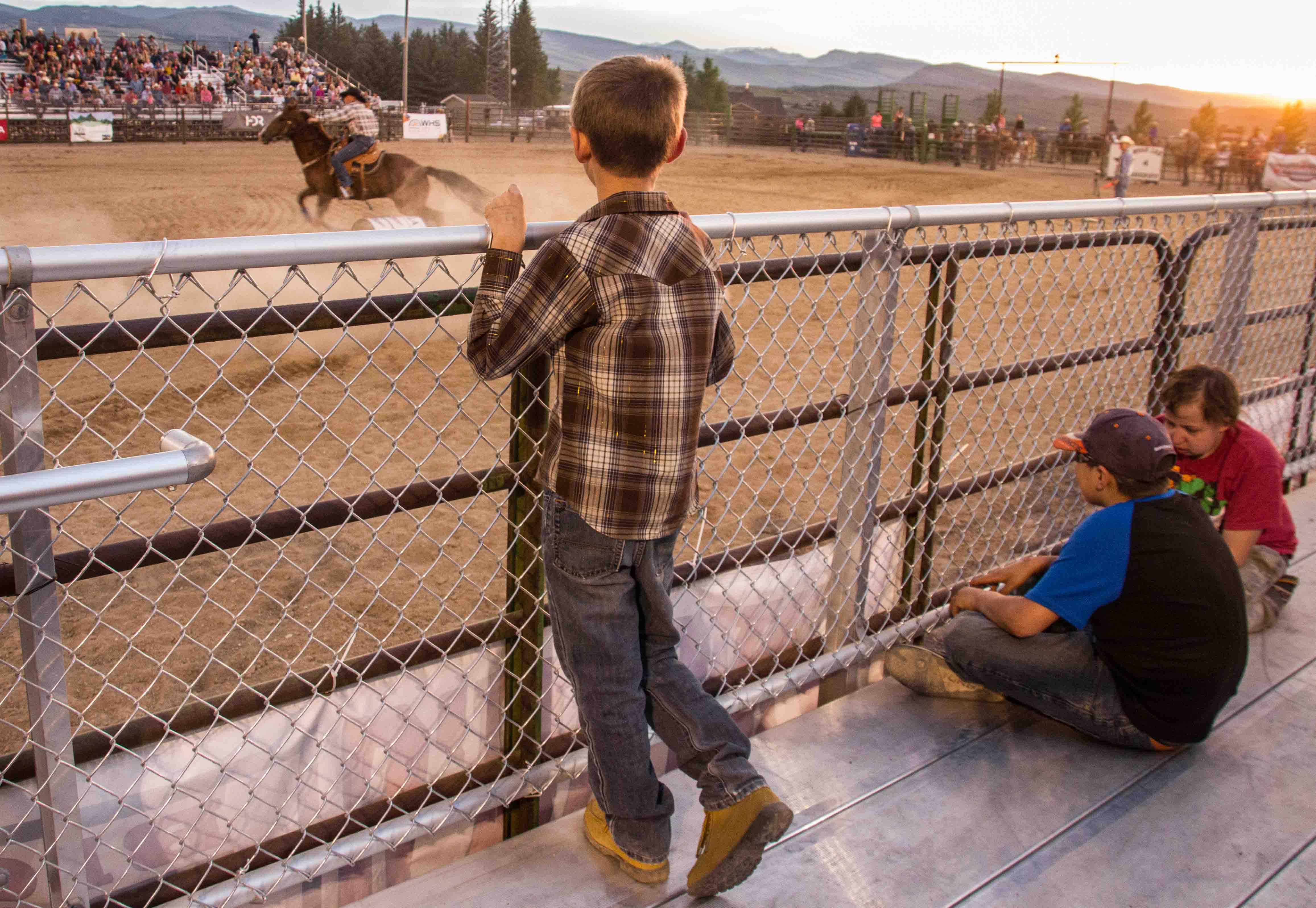 Youth rodeo audience members watch the barrel races from the grandstand deck.